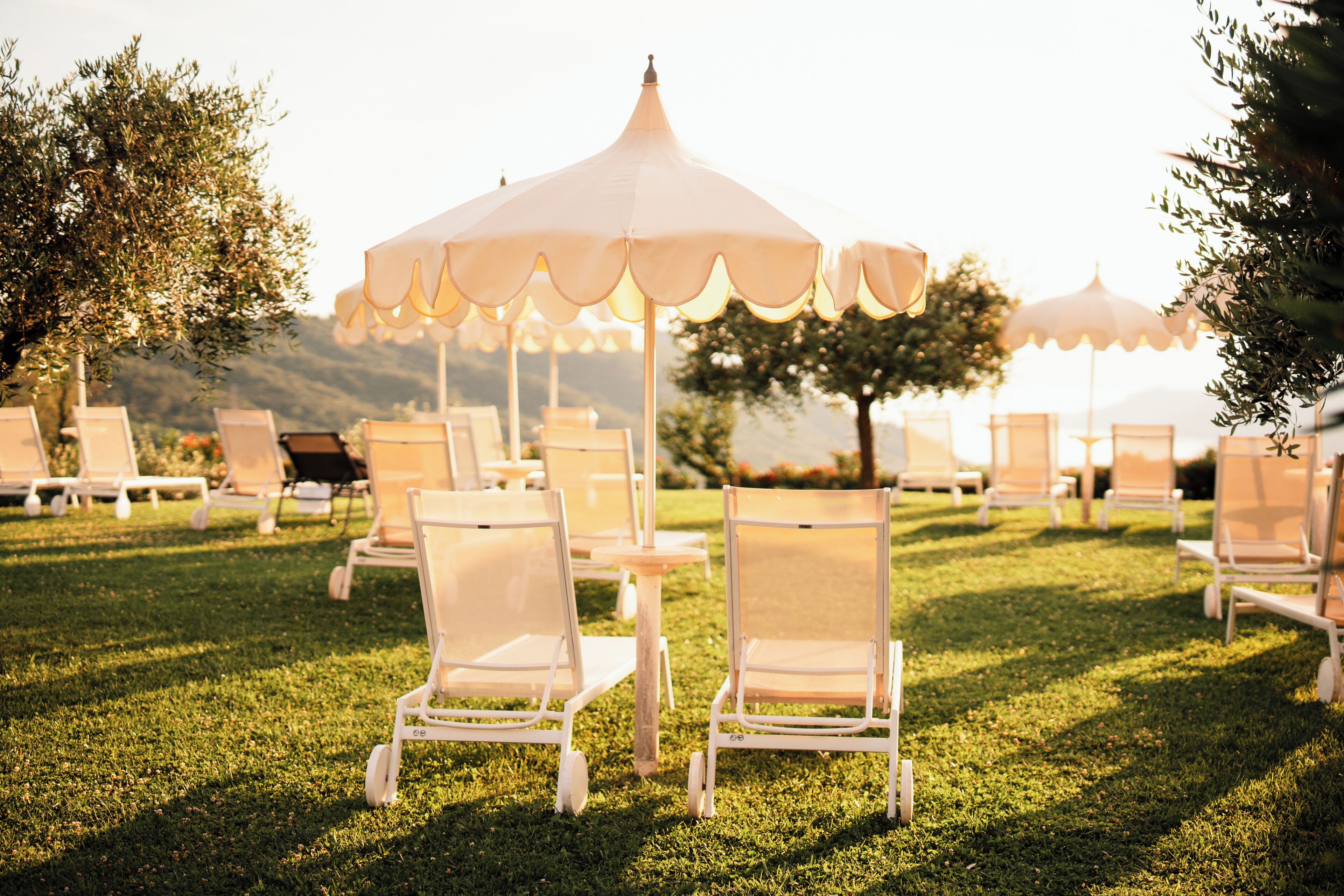 Outdoor seating with umbrellas and chairs arranged on a grassy area.