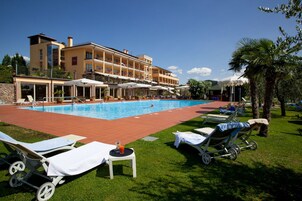 Una piscina techada, una piscina al aire libre, sombrillas