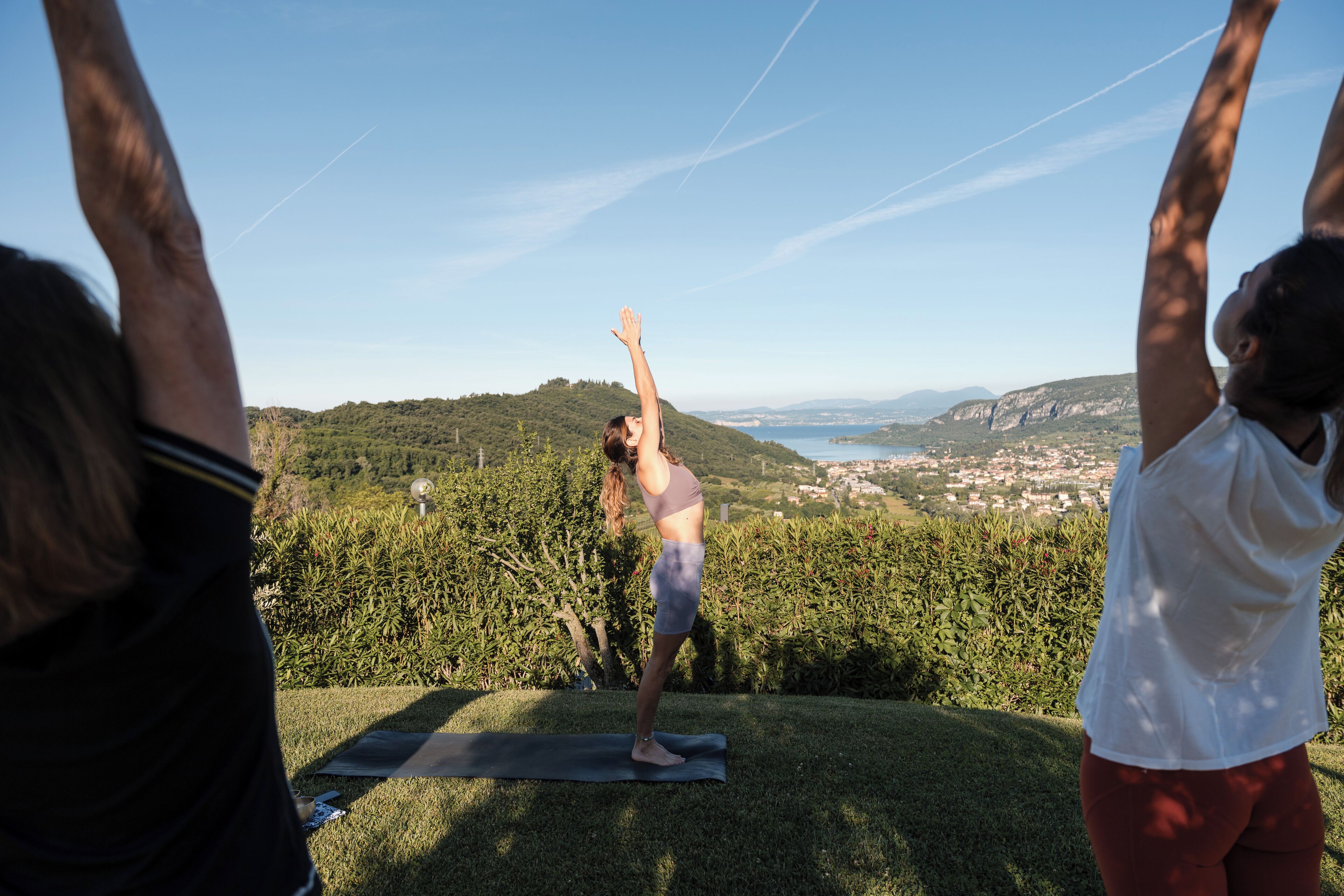 Iemand doet yoga op een matje buiten, met een mooi uitzicht op heuvels en een stad op de achtergrond.