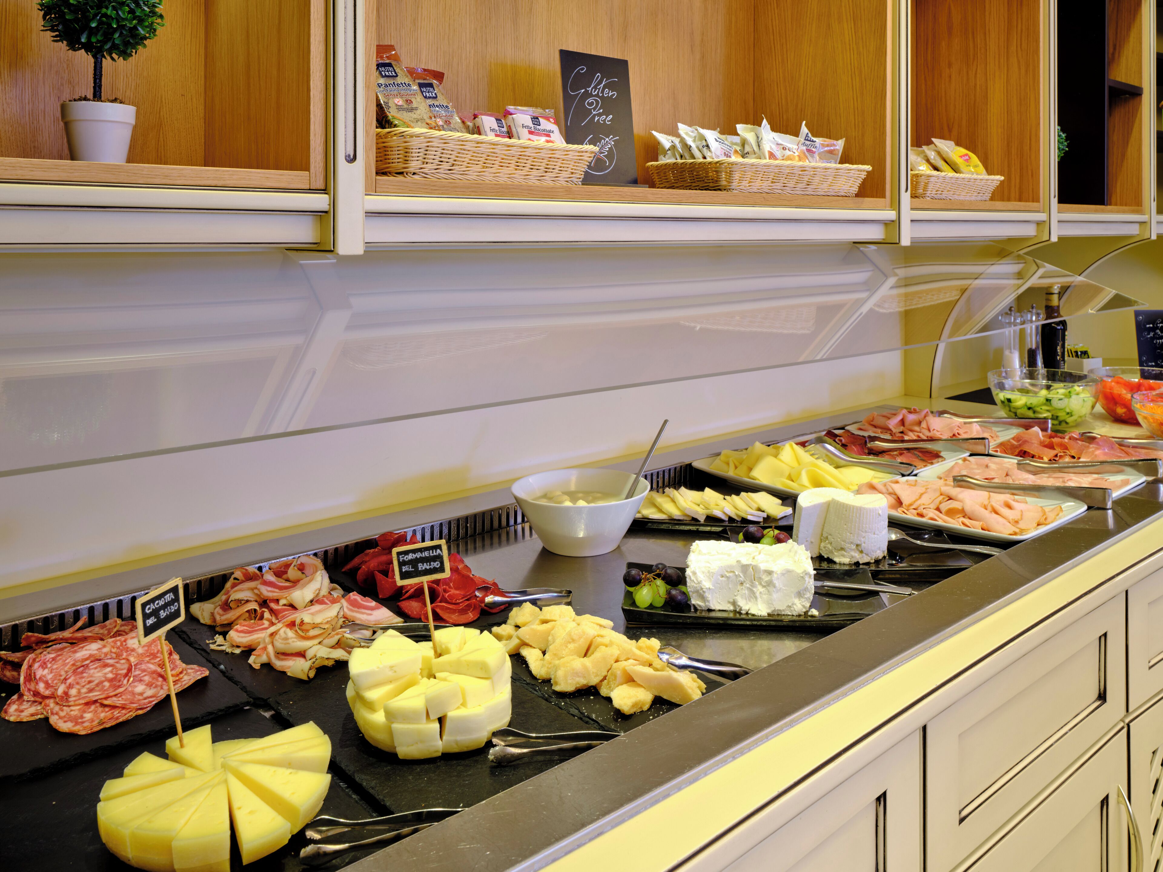 A buffet with various food items including cheese, meats, and fruits.