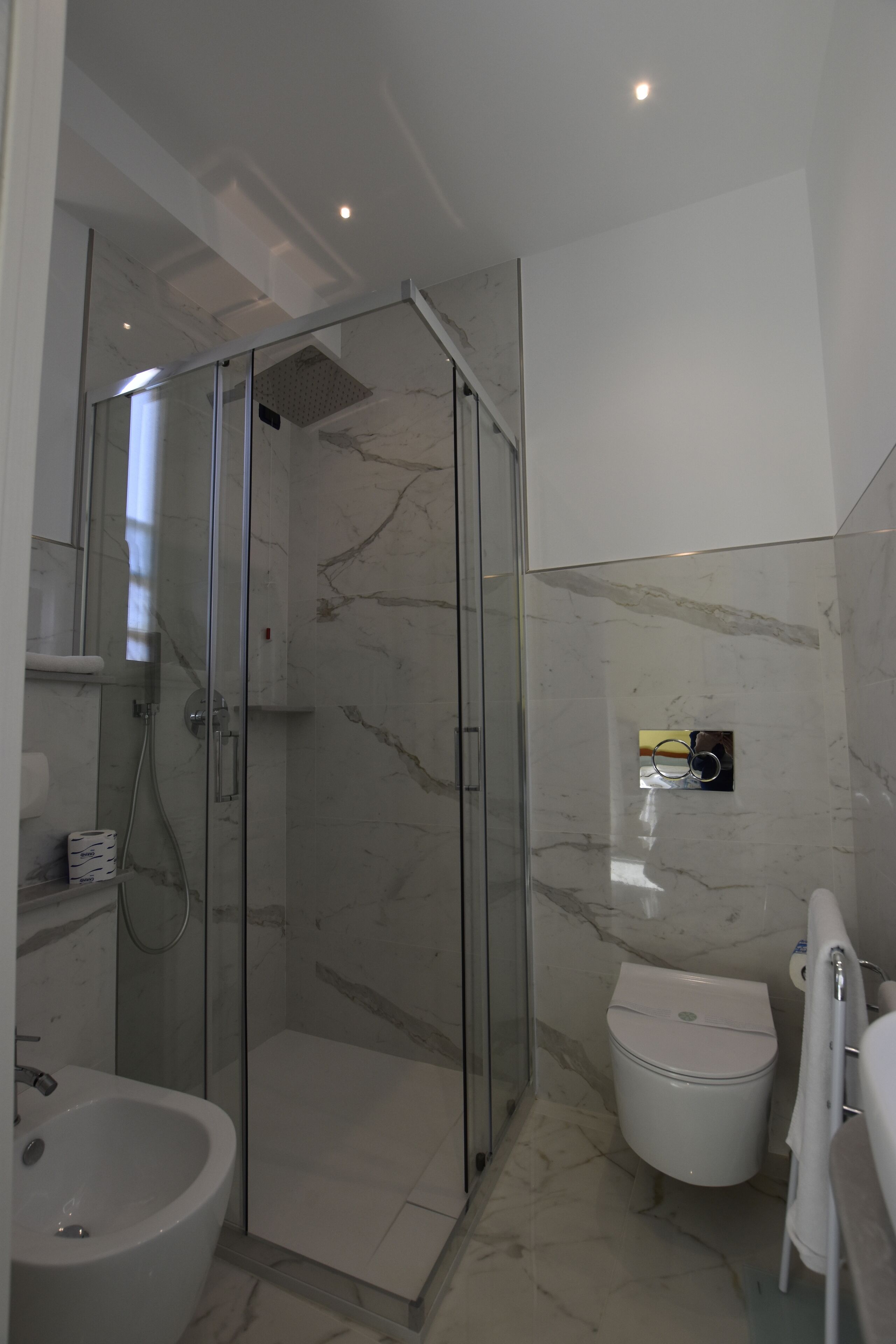 Een moderne badkamer met een douchecabine van glas, een wit toilet en een wastafel.