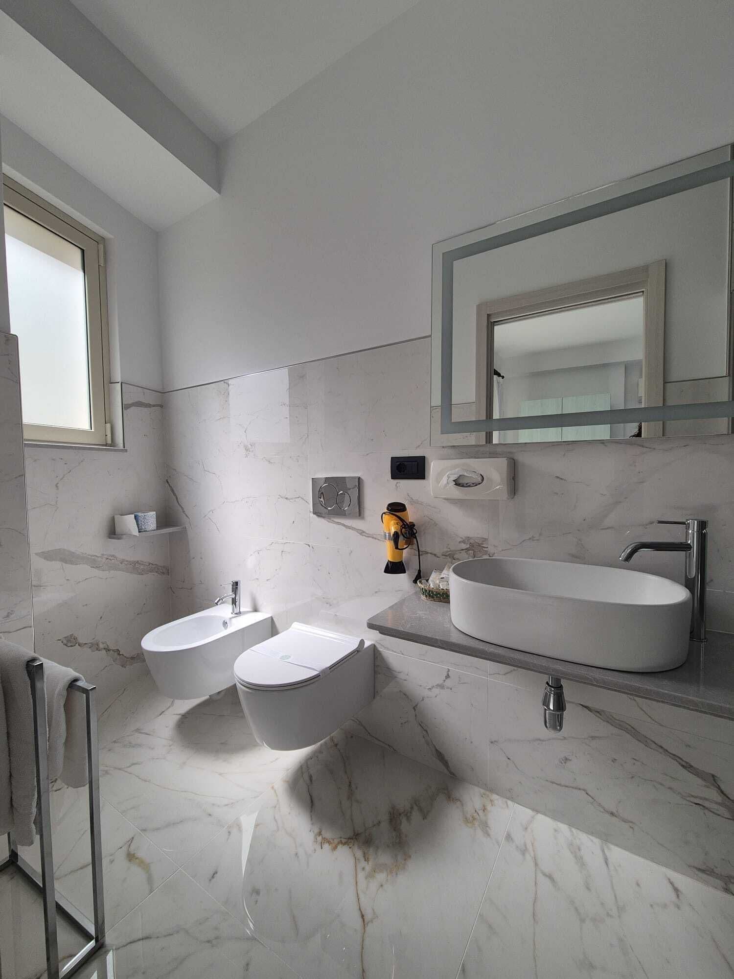 A modern bathroom with a large bathtub, two sinks, a mirror, and a towel rack.