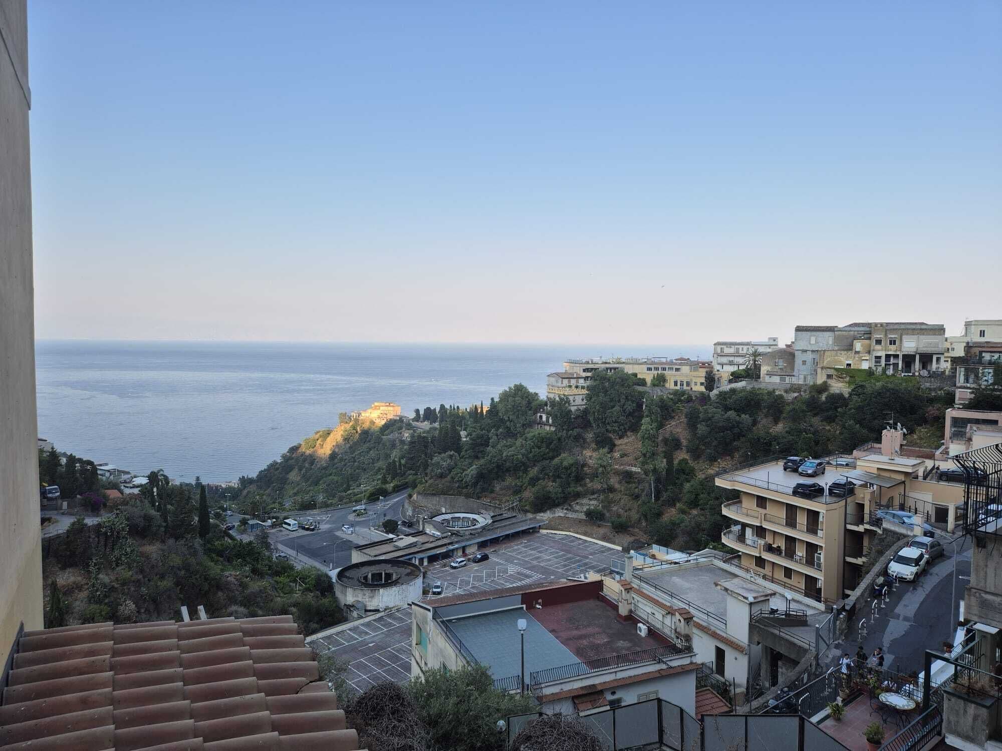 Un barrio residencial con vista al mar, edificios con balcones y un estacionamiento.