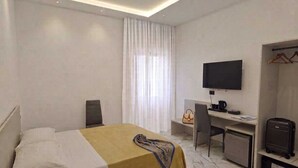 Una habitació d'hotel amb un llit, una taula de nit amb ordinador, televisió i un armari.