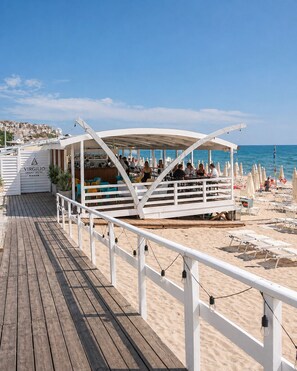 A beachside restaurant with outdoor seating, a wooden deck, and a view of the sea. - Virgilio Grand Hotel (Sperlonga)