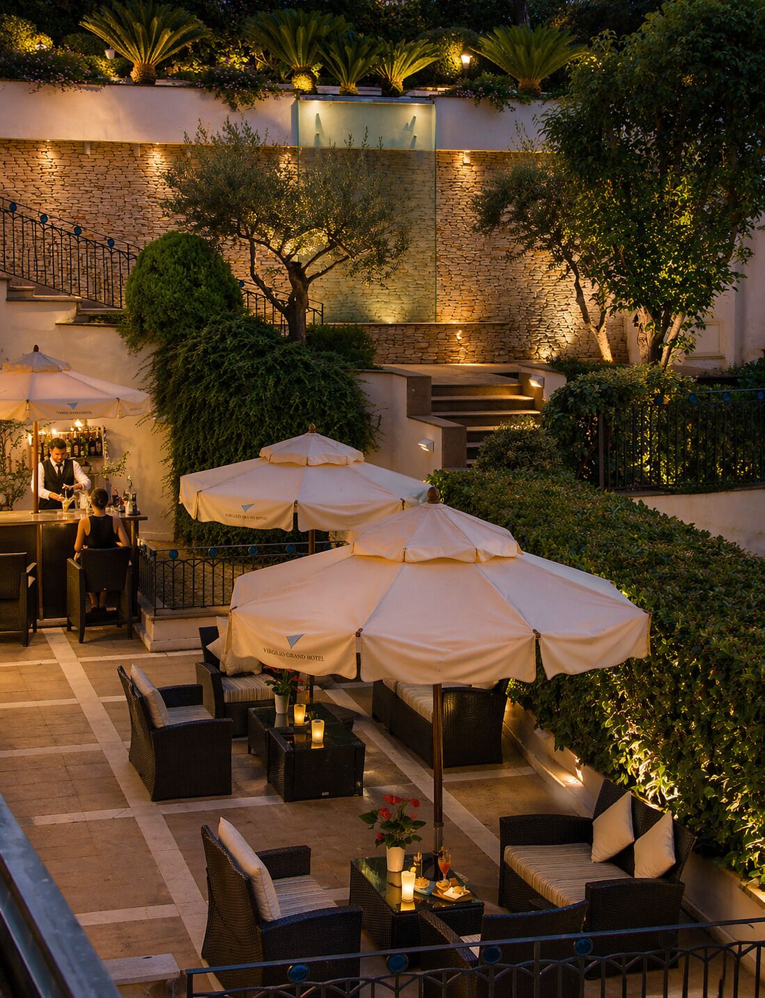 An outdoor patio area with multiple seating arrangements, umbrellas, and a bar area.