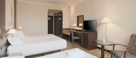 A hotel room with two beds, a desk with a chair, a television, and a lamp.