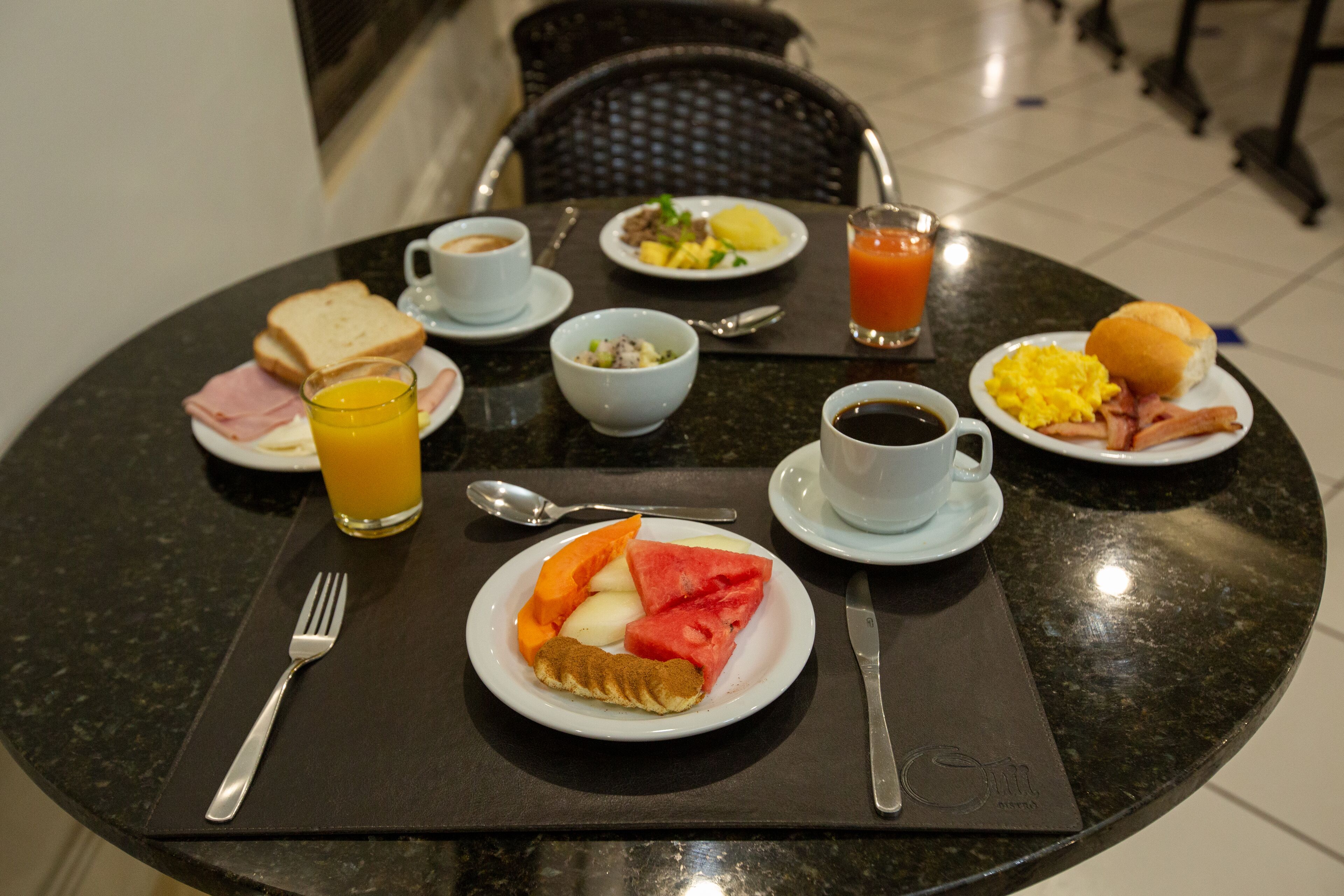 Ett frukostbord med tallrikar fyllda med mat, dryck och bestick.