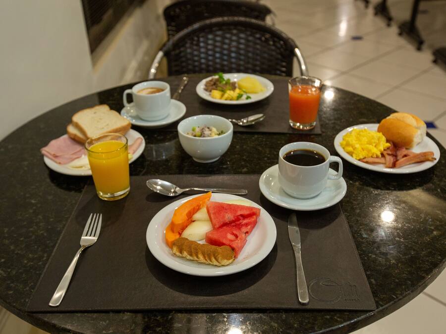 Una mesa de desayuno con platos de comida, bebidas y cubiertos.