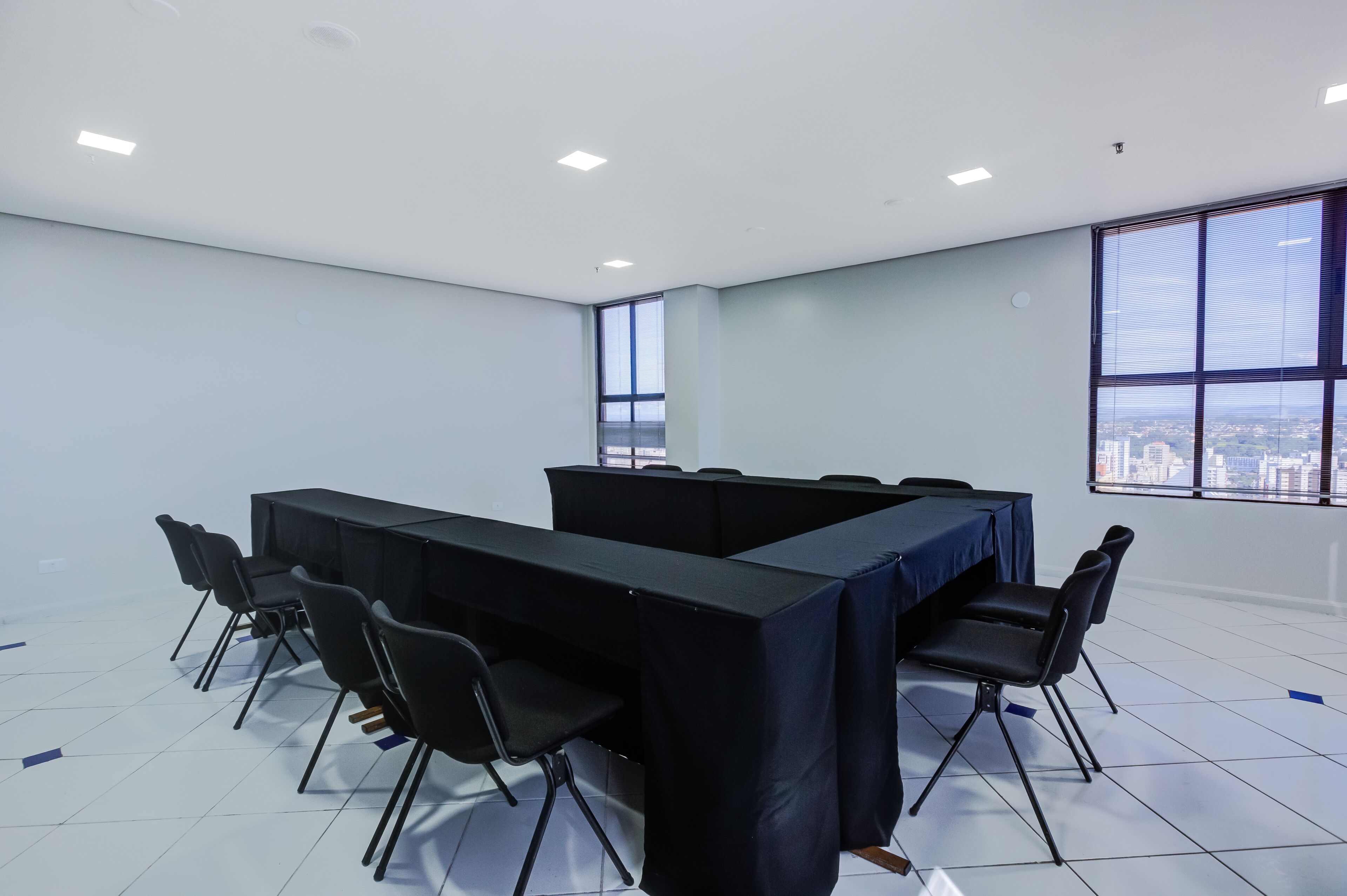 Ein Konferenzraum mit langem Tisch, schwarzen Stühlen und großen Fenstern mit Blick auf die Stadt.