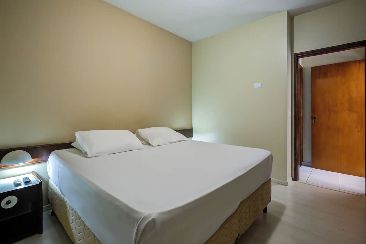 Une chambre d’hôtel avec un lit, une table de chevet et une porte en bois.