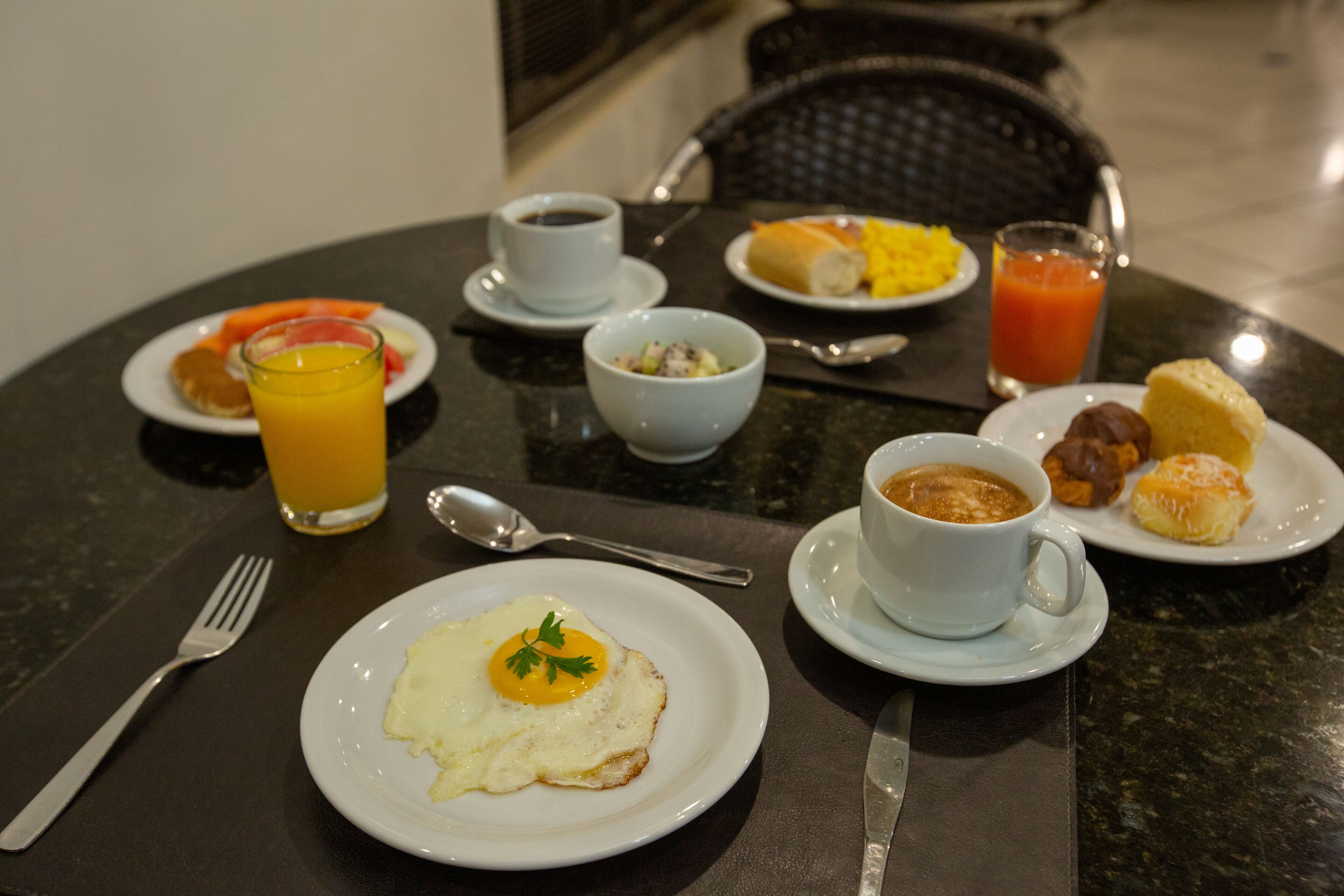 A breakfast table with plates of food, a glass of orange juice, and a cup of coffee.