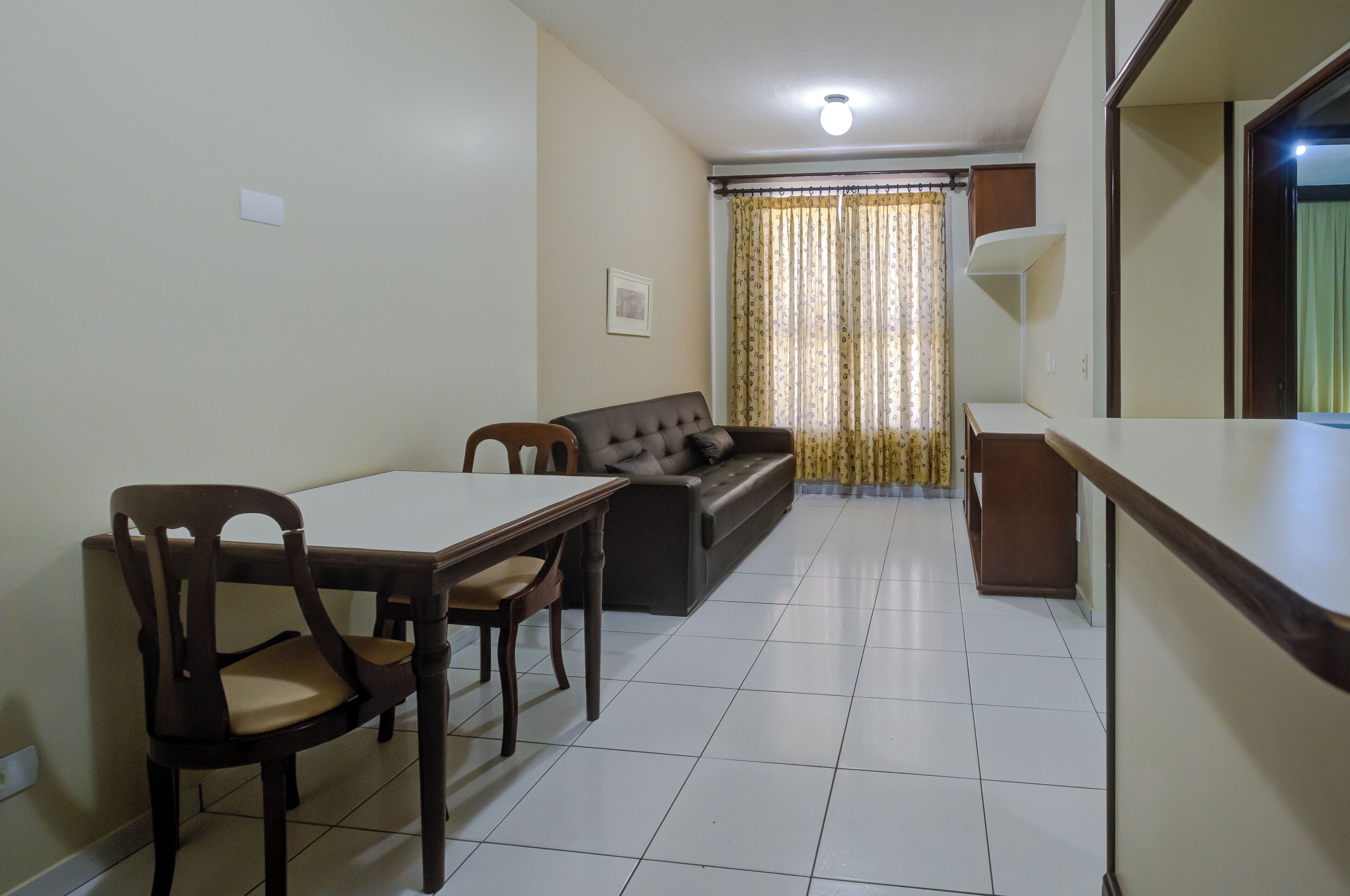 Un comedor con una mesa y sillas, un sofá y una ventana con cortinas.