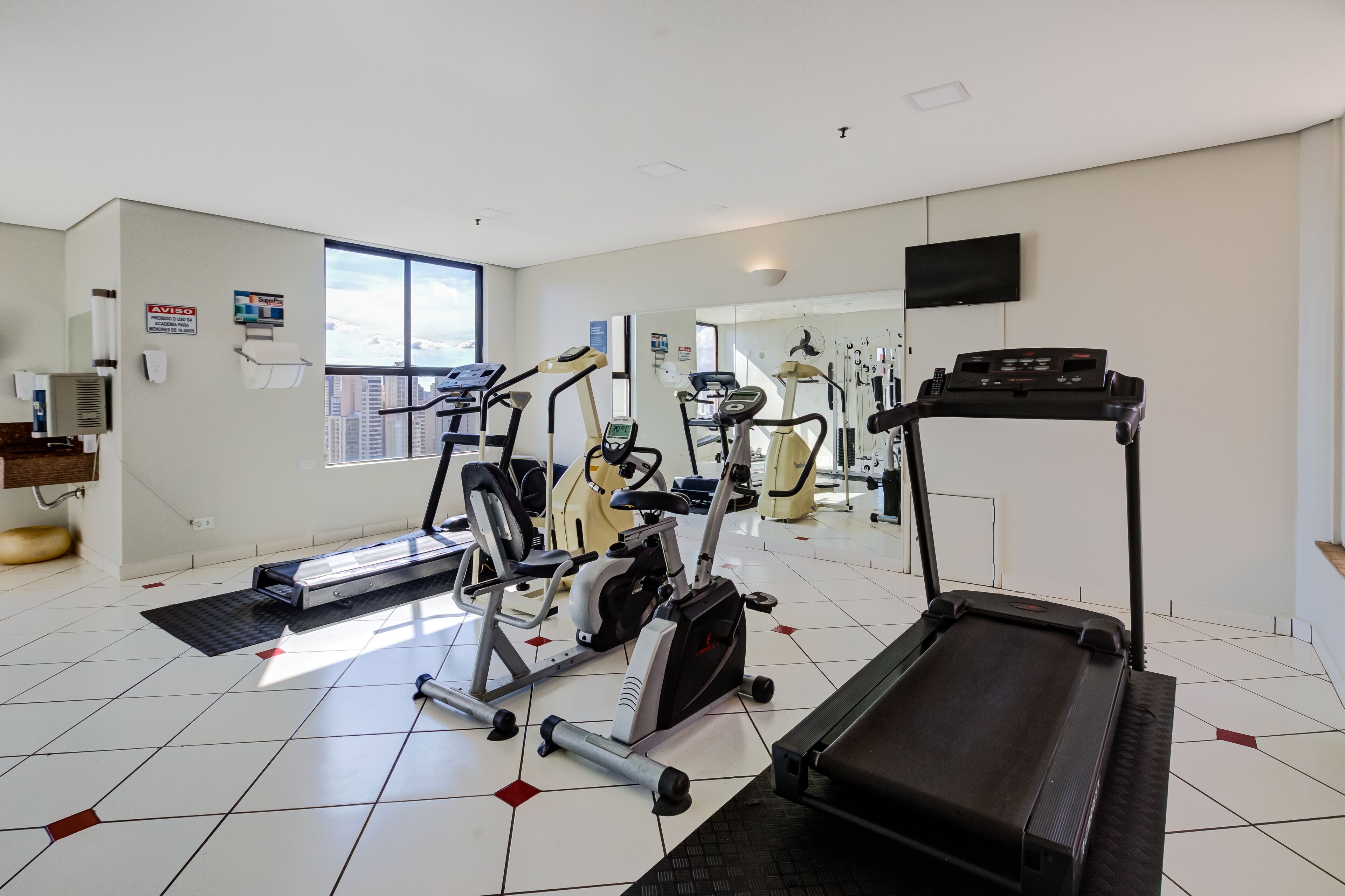 Ein Fitnessstudio mit Laufbändern, Crosstrainern und einem stationären Fahrrad.