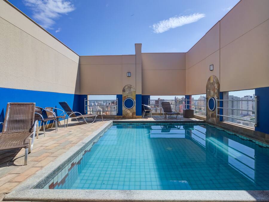 A rooftop pool with lounge chairs and a city view.