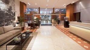Un hall de hotel con mostrador de recepción, zona de estar y un mural grande en la pared.