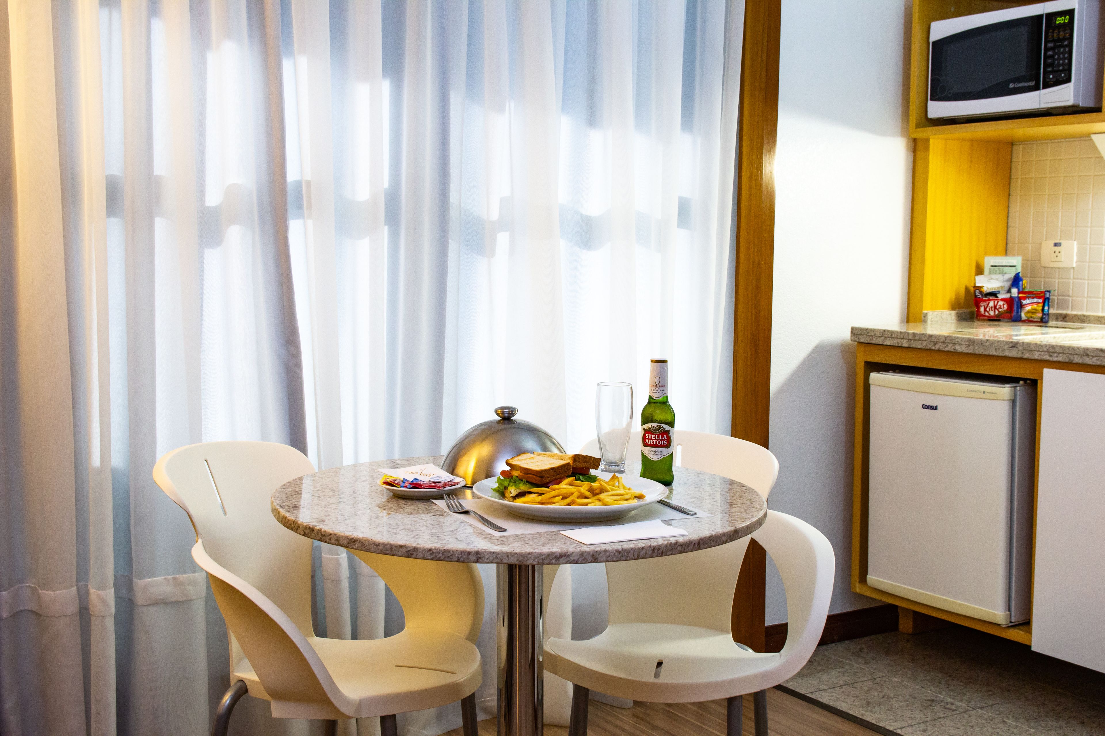 Un petit coin repas avec une table dressée pour deux personnes, un four à micro-ondes et un réfrigérateur.