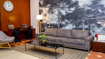 A modern living room with a sofa, a coffee table, a lamp, and a clock on the wall.