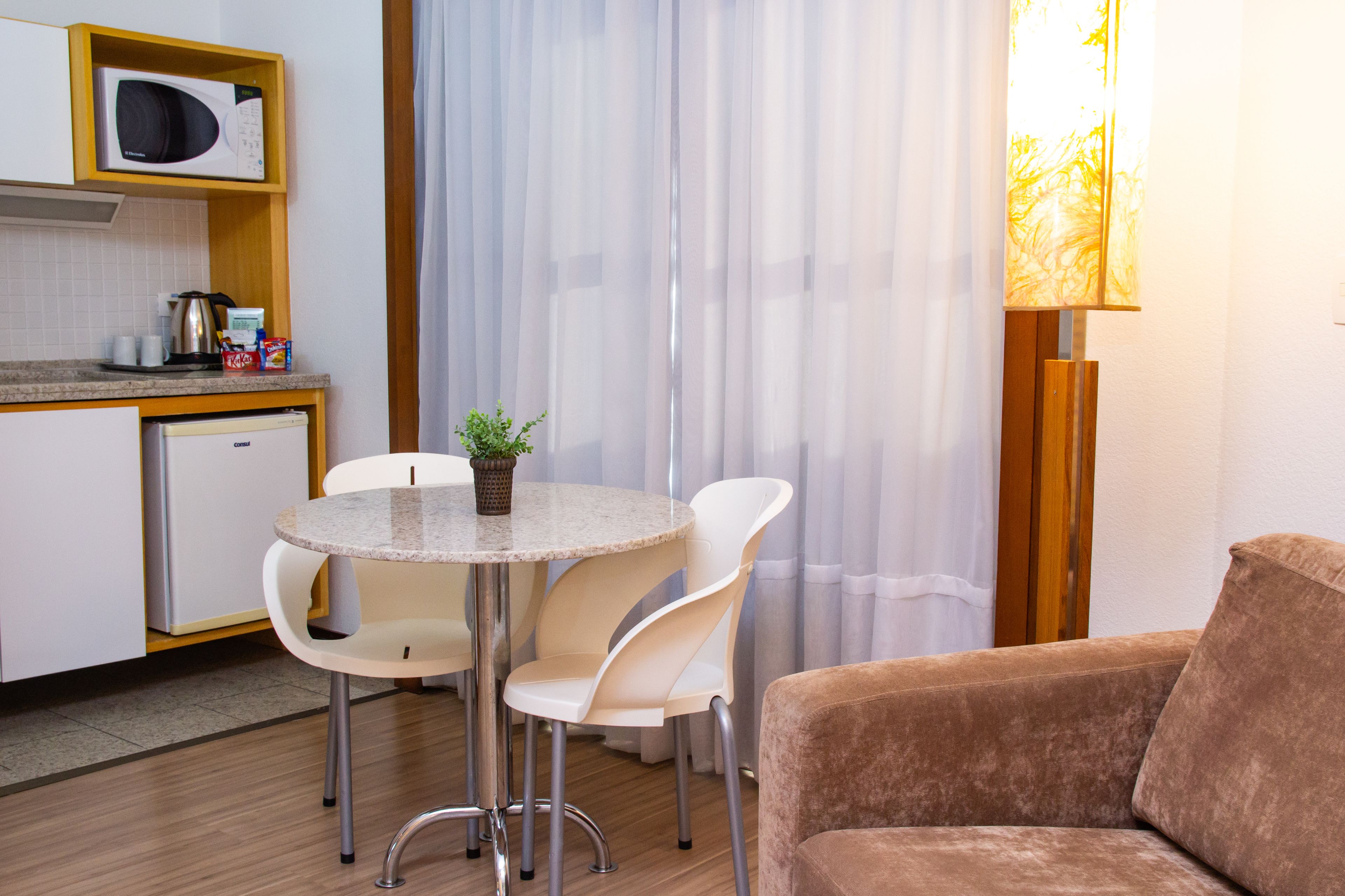 Un espacio habitable compacto con kitchenette, una zona de comedor con mesa y sillas, y un sofá.