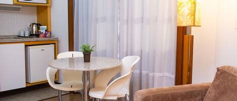 Un espacio habitable compacto con kitchenette, una zona de comedor con mesa y sillas, y un sofá.
