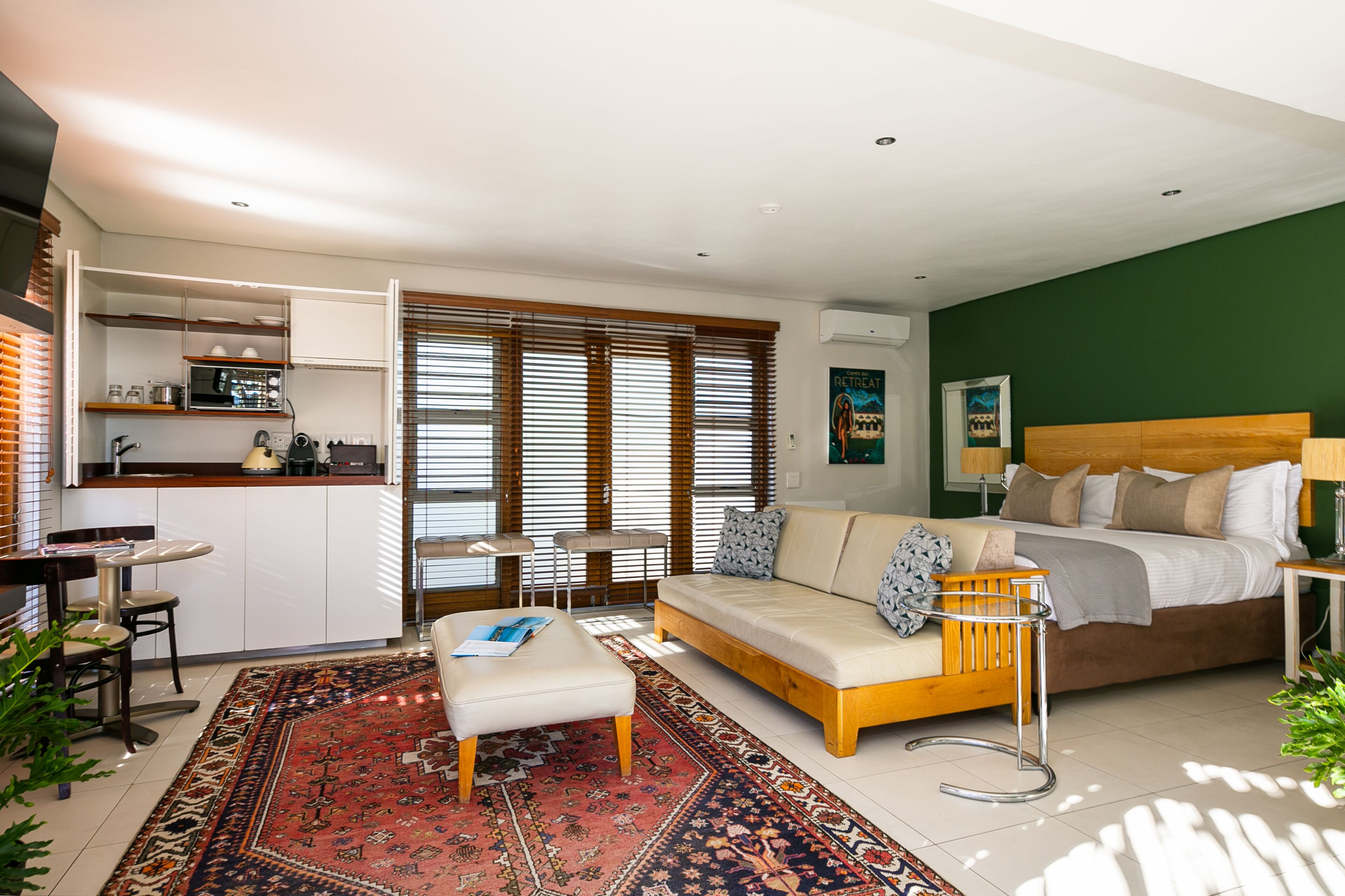 Un appartamento moderno con angolo cottura, divano, zona pranzo e camera da letto con letto e comodino.