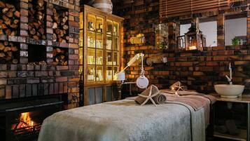 Cozy room with a brick fireplace, a comfortable bed, and a large mirror.
