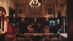 A grand lobby with a chandelier, a fireplace, and a bar area.