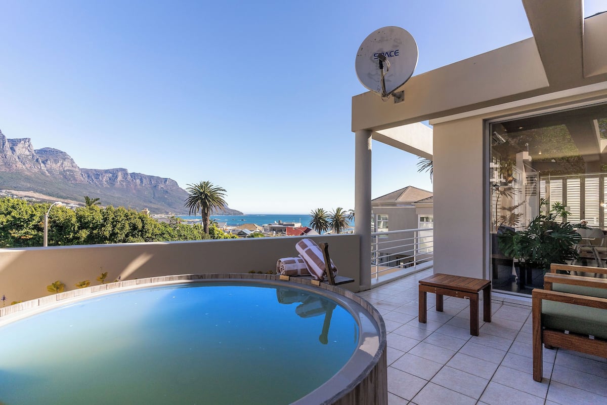 A rooftop pool with a clear view of the ocean and mountains, a satellite dish, and outdoor furniture.