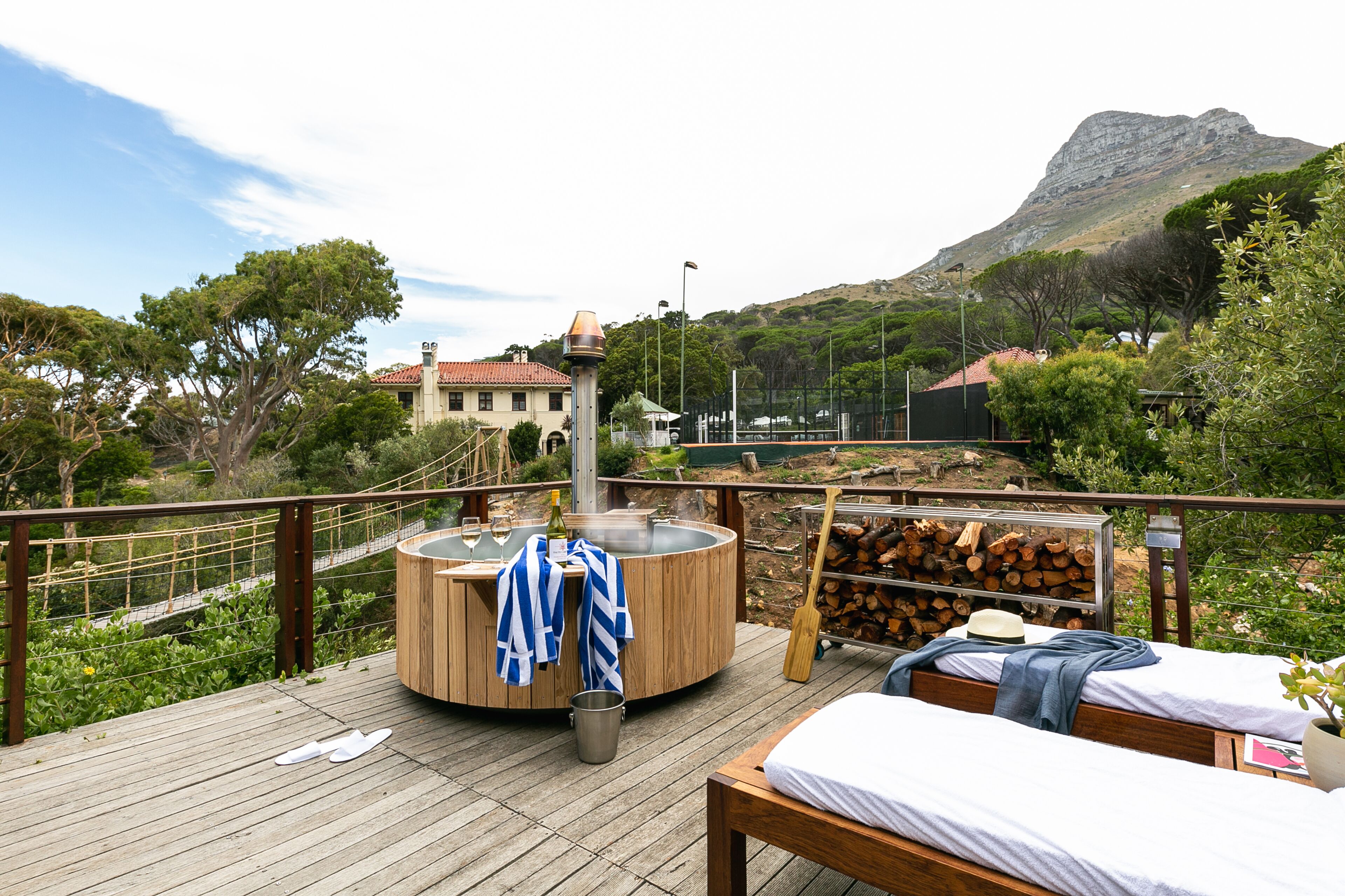 A wooden deck with a hot tub, a bed, and a view of a mountain.