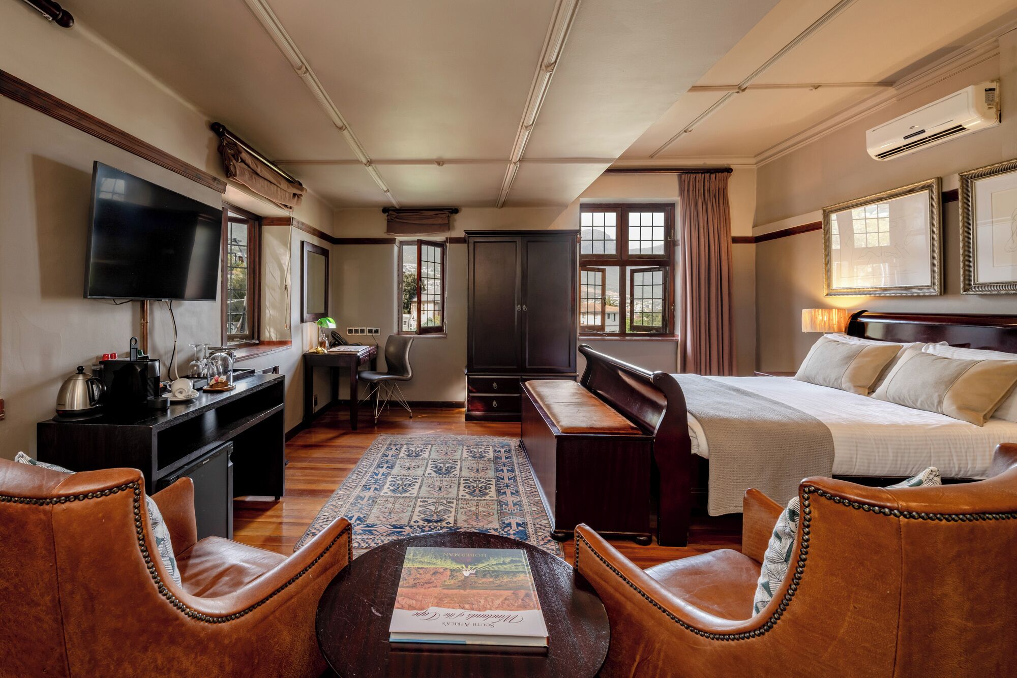 A hotel room with a bed, a desk with a computer, a television, a coffee maker, and a window with curtains.