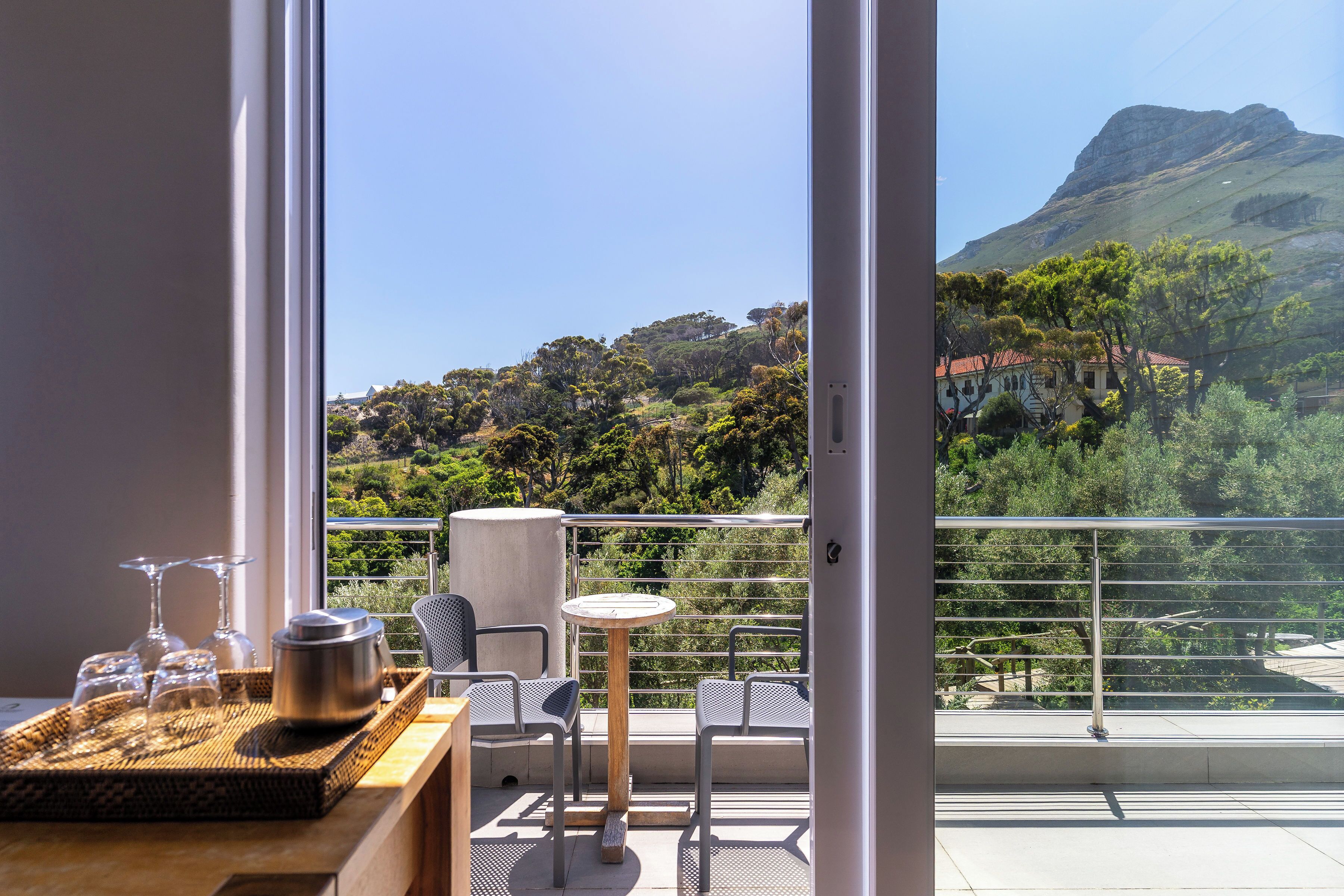 A balcony with a table, chairs, and a view of a mountainous landscape.