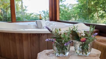 Eine Holzwanne mit einer Glasvase voller Blumen auf einem Holztisch.