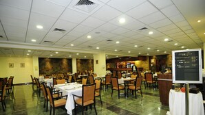 Un comedor amplio con varias mesas y sillas, una barra de buffet y un panel con el menú.