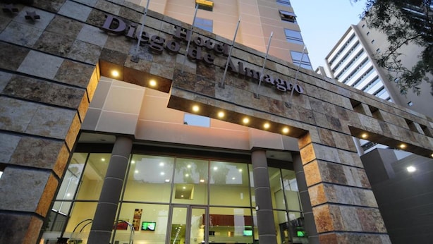 Exterior del Hotel de Madrid, con fachada de piedra y un amplio acceso de vidrio.