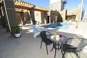 A rooftop pool area with lounge chairs, a table with drinks, and potted plants. - Diego De Almagro Calama (Calama)