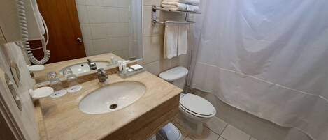 A bathroom with a beige sink, a mirror, a toilet, and a shower curtain.