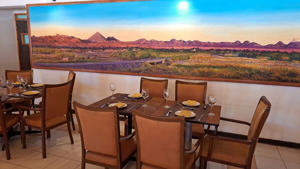 A dining area with a table set for six, chairs, and a large landscape painting on the wall. - Diego de Almagro San Pedro de Atacama (San Pedro de Atacama)