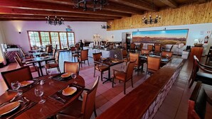 A spacious dining area with multiple tables and chairs, wooden beams on the ceiling, and a large painting on the wall. - Diego de Almagro San Pedro de Atacama (San Pedro de Atacama)