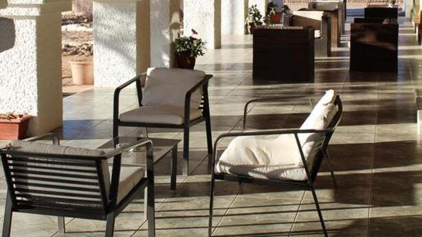 An outdoor patio area with tiled flooring, seating arrangements, and arched columns. - Diego de Almagro San Pedro de Atacama (San Pedro de Atacama)