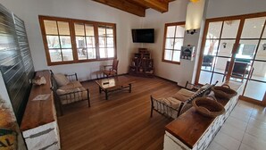 A spacious living area with wooden flooring, a sofa, a coffee table, and a TV mounted on the wall. - Diego de Almagro San Pedro de Atacama (San Pedro de Atacama)