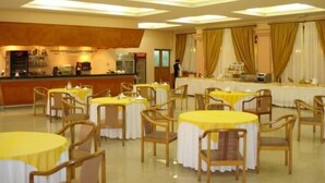 Un comedor con mesas redondas cubiertas con manteles amarillos y sillas de madera.