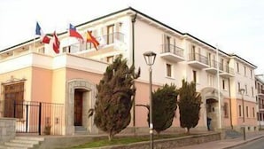 Un edificio de varios pisos con fachada rosa, múltiples balcones y una exhibición de banderas.