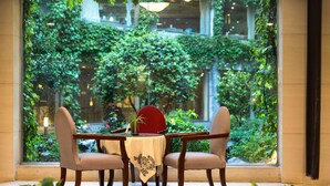 A dining area with a table and four chairs, a vase, and a red object on the table.