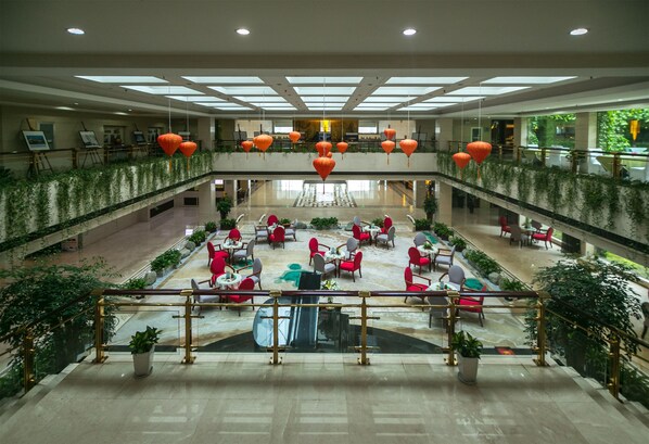 Un vaste atrium intérieur doté d’un espace salon central, de plusieurs niveaux et de lanternes suspendues.