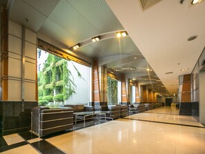 Eine moderne Lobby mit einer langen Rezeption, einer Sitzecke und großen Fenstern mit Bepflanzung.