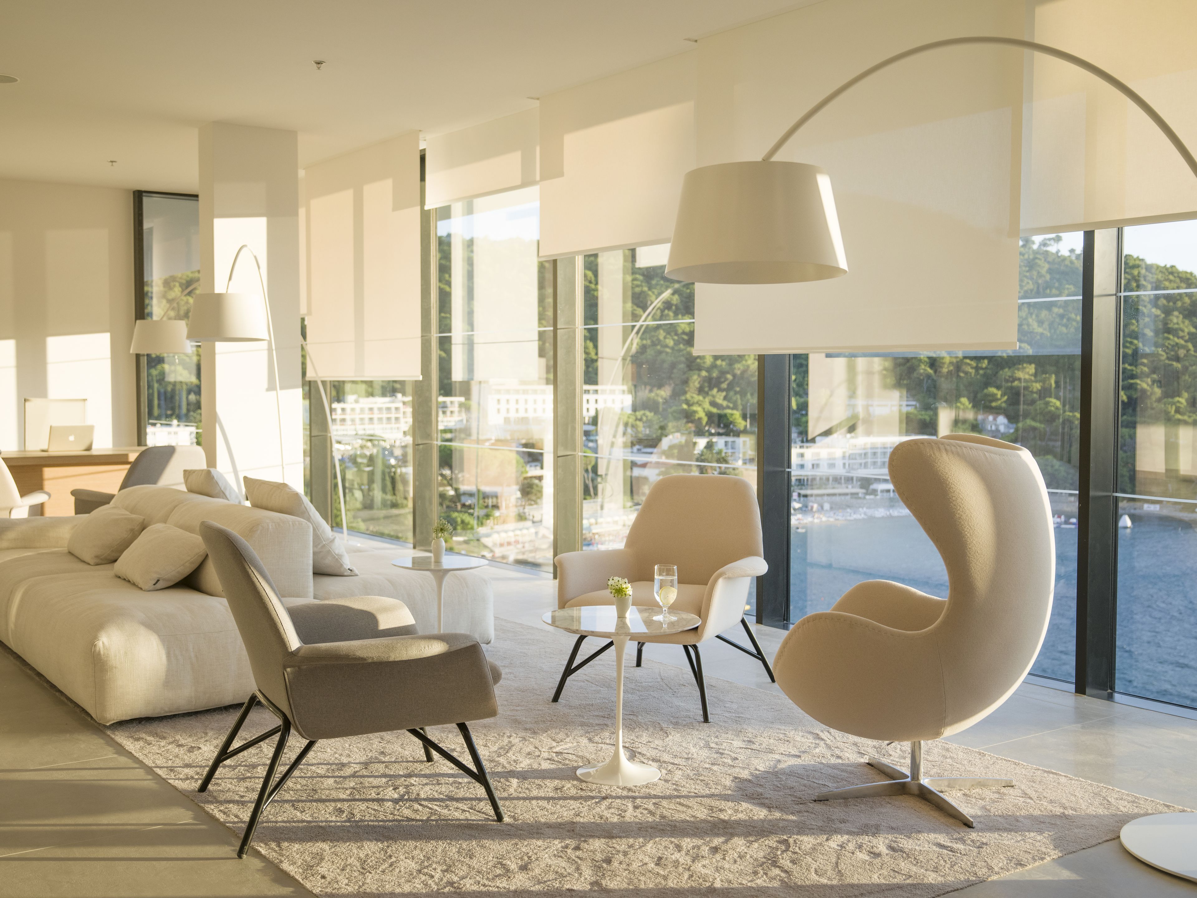 Uma sala de estar moderna com uma janela grande, um sofá, duas poltronas, uma mesa de centro e um abajur.