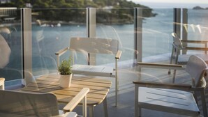 A balcony with a wooden table, chairs, and a potted plant. - Hotel Kompas (Dubrovnik)