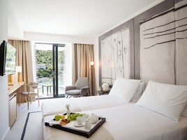 Quarto de hotel com cama, escrivaninha, cadeira, televisão e mesa de jantar com itens de café da manhã.