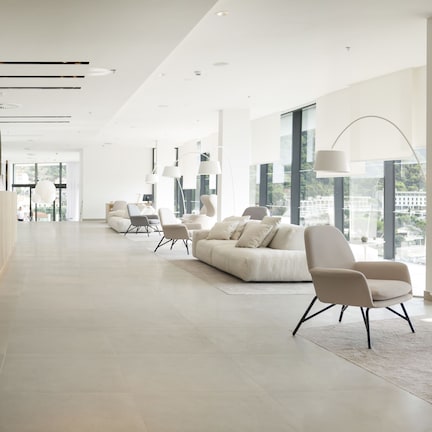 A spacious lobby with a reception desk, modern seating, large windows, and a view of the city.