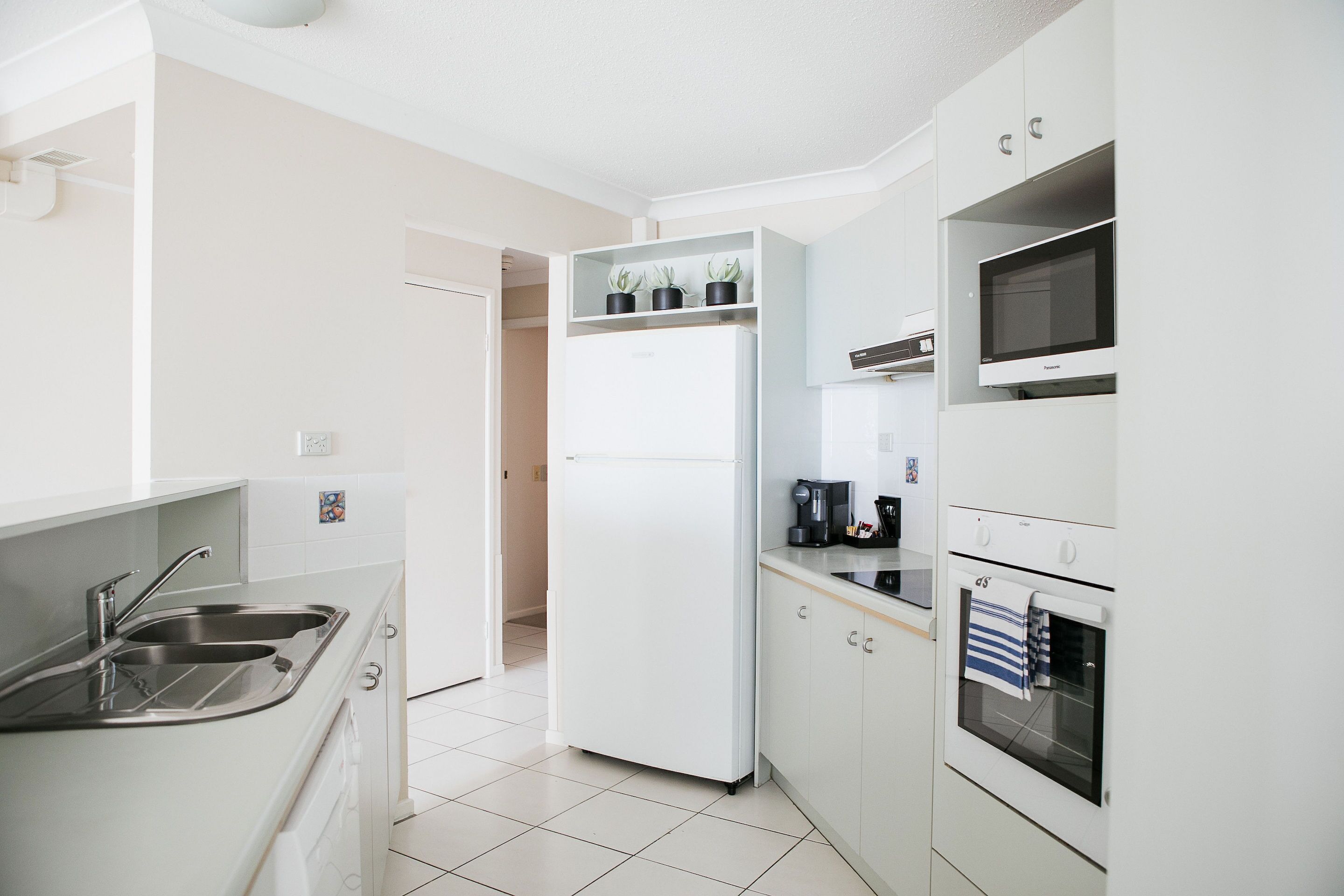 A modern kitchen with a built-in refrigerator, microwave, oven, and a coffee maker.